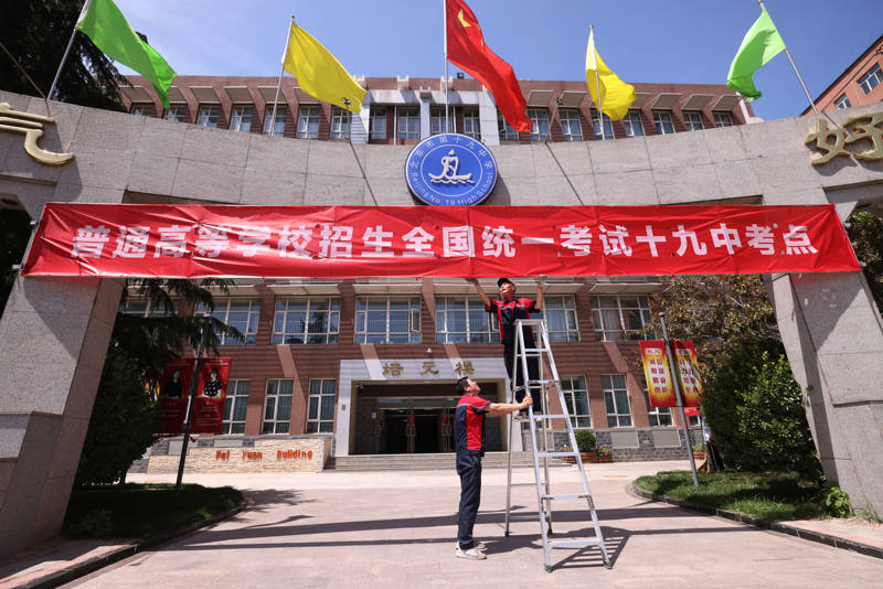北京市第十九中学考点,工作人员正在挂横幅。新京报记者 李木易 摄